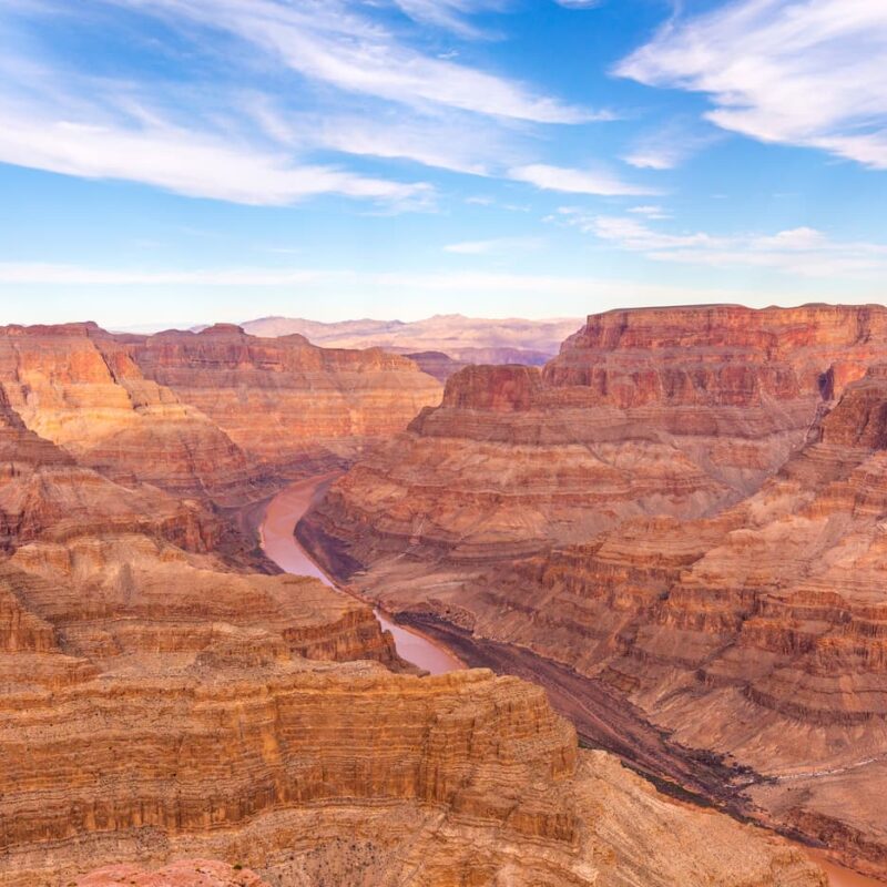 Wide panoramic view of the Grand Canyon with the muddy Colorado River running through it.