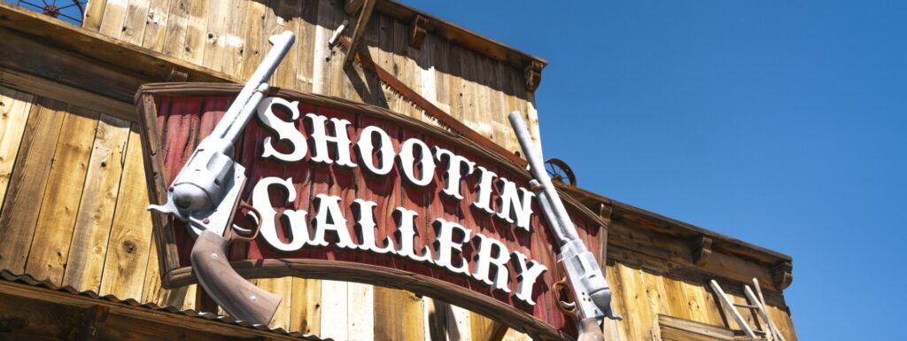 Punta Hualapai A "Shootin' Gallery" sign with two cowboy revolvers hangs on a wooden building.
