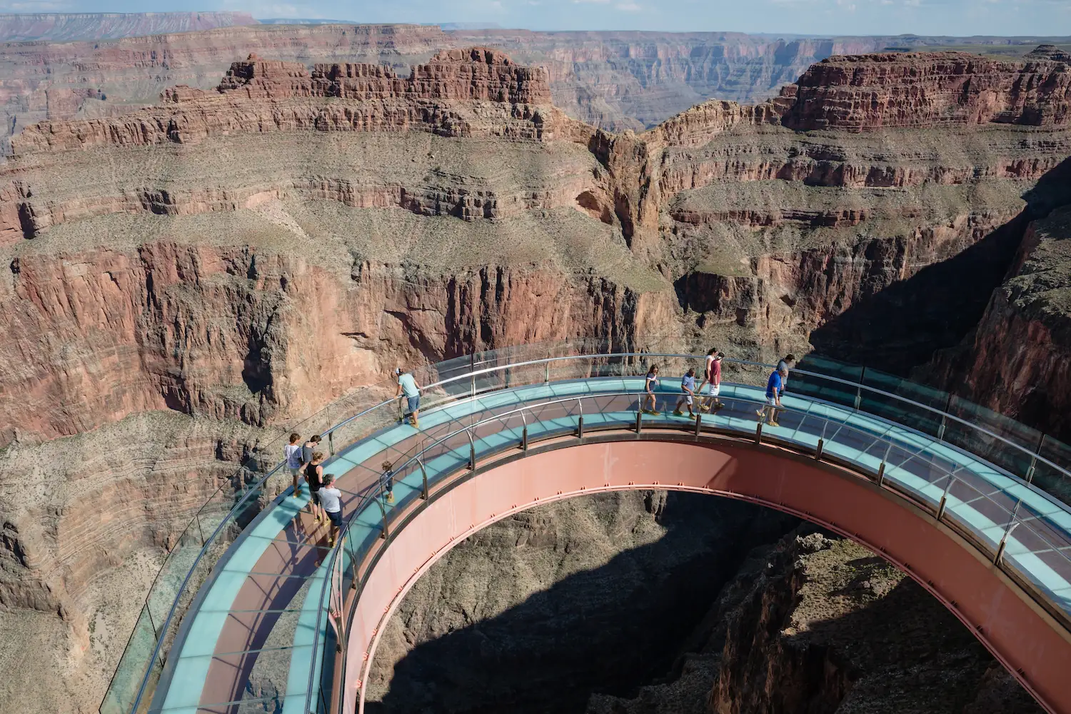 Skywalk Highlight Tourists standing on the curved glass-bottom Grand Canyon Skywalk, suspended over deep canyon cliffs with breathtaking panoramic views.